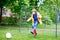 Active cute little kid boy playing soccer and football and having fun