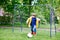 Active cute little kid boy playing soccer and football and having fun, outdoors. Child having game on rainy day. Wearing