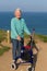 Active elderly lady pensioner in eighties with three wheel mobility frame by coast