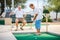 Active elderly senior couple playing miniature golf together