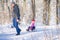 Active family holidays for adults and children. A man rides a little girl on a sled in the winter forest. Grandfather takes his