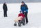 Active father skating with infant in baby carriage on a frozen river Dnepr