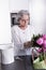 Active female pensioner is preparing flowers for the vase