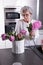 Active female pensioner is preparing flowers for the vase