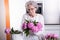 Active female pensioner is preparing flowers for the vase