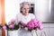 Active female pensioner is preparing flowers for the vase