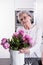 Active female pensioner is preparing flowers for the vase