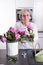 Active female pensioner is preparing flowers for the vase