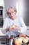 Active female senior peeling apple in the kitchen