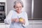 Active female senior peeling apple in the kitchen