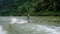 Active fit Asian athlete on a wakeboard on the river with forest background