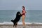 Active friendly family dog breed Bernese Mountain Dog is on vacation on beach. Young pretty Caucasian red haired girl is standing