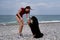 Active friendly family dog breed Bernese Mountain Dog is on vacation on beach. Young pretty Caucasian red haired girl is standing