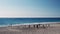 Active friends playing beach volleyball on sandy beach. People pass and spike ball over net on sunny summer day near sea. Friends