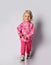 Active frolic smiling blonde baby kid girl in pink warm fleece clothing with heart print pattern walks towards camera