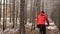 Active girl cycling with her dog. The woman in the winter wood goes between larches.