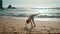 Active girl making gymnastics elements in front beautiful ocean waves sunny day.