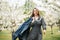 Active girl in retro dress and denim jacket in a blooming apple orchard. lifestyle activity outdoor.