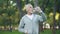 Active grandfather drinking water after workout in park, health care, sport