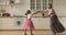 Active granny dance waltz with little granddaughter in kitchen