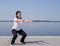 Active and happy senior woman squatting near the riverside