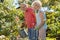 Active happy senior woman standing next to her husband during garden work