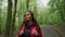 Active healthy female hiking along forest road. Portrait of beautiful woman tourist in red jacket and sunglasses