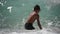 active healthy kid in diving mask playing in blue sea with high waves during ocean storm in summer sunny day