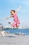 Active kid girl gymnast jumping or dancing on the street. Young girl acrobat. The girl is engaged in gymnastics.