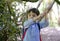 Active kid holding branch tree in the park, Excited boy carrying backpack getting adventure in the forest tree with school camp,