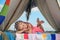 Active kid lifestyle. Smiling child in tent. Girl playing in camp. Outdoor camping and having fun at campground.