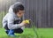 Active kid using spray bottle watering flowers in the garden, Child spraying water on daffodils flowers, Cute boy having fun with