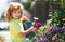 Active kid watering plants on backyard. Child helping arents to grow herbs and flowers in garden.