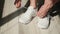 active lifestyle, female hands tying laces on sports white sneakers for a walk on the street, close-up