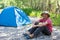 Active lifestyle in old age concept. camping, tourism in the elderly grow. an old man in a hat smiles and sits near the tent