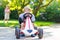 Active little boy driving pedal car in summer garden