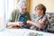 Active little preschool kid boy and grand grandmother playing card game together at home