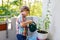 Active little preschool kid boy watering plants with water can at home on balcony