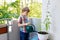 Active little preschool kid boy watering plants with water can at home on balcony