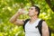 Active man drinking water from a bottle, outdoor. Young muscular male quenches thirst