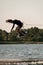 active man holding rope and making trick in jump time with wakeboard over water