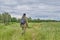 Active man in mosquito suit with backpack in hiking in a meadow. Siberia, Russia