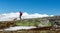 Active man in red jacket are walking in the wilderness with his dog with snow capped mountains in the back and blue sky