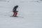 Active man ski riding on slope. Male freeride skier moving on white snow. Side view of male in gray coat and red pants rides