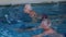 Active mature couple swimming in hotel water pool