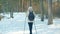 Active mature woman enjoying nordic walking with ski poles in winter forest