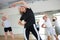 Active mature woman performing stretching during group training