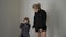 active mother in a black sweater and with her daughter in jacket fooling around and dancing at home during the day