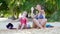 Active mother and daughter listen to music and dance on sandy beach on green palm tree background