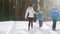 Active mother with two children is walking along the snow-covered forest